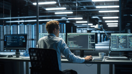 IT Specialist Uses Computer in Data Center. Server Farm Cloud Computing Facility with Male...