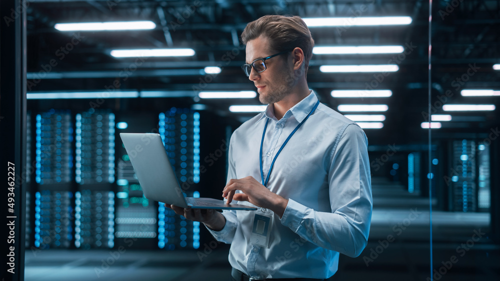 Poster european male it specialist using laptop computer, standing in big warehouse data center. system adm
