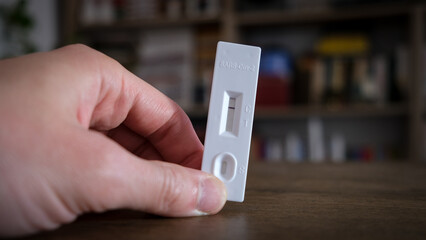 Closeup photo with a hand holding a negative coronavirus test inside a home