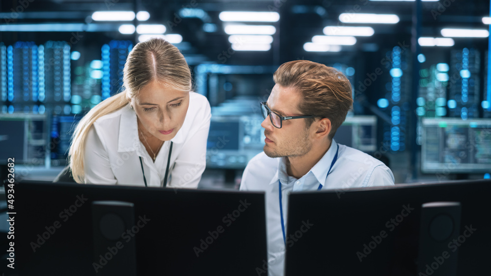 Poster IT Specialist Works on Two Personal Computer at the Software Program with Coding Language Interface. In the Background Technical Room of Data Center with Professional Working
