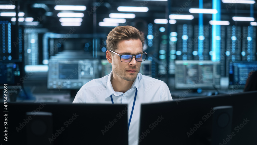 Poster focused system administrator or consultant look at the screen and saves backup data in dark evening 