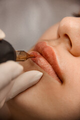beauty procedure.  closeup permanent lip tattoo. master in white medical gloves makes permanent lip...