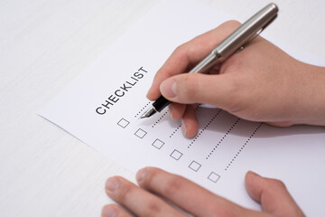 Close-up Of Person's Hand Marking On Checklist Form