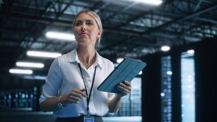 Woman IT Technician Works on Tablet Computer in Big Data Center at Night. She Runs Diagnostics and...