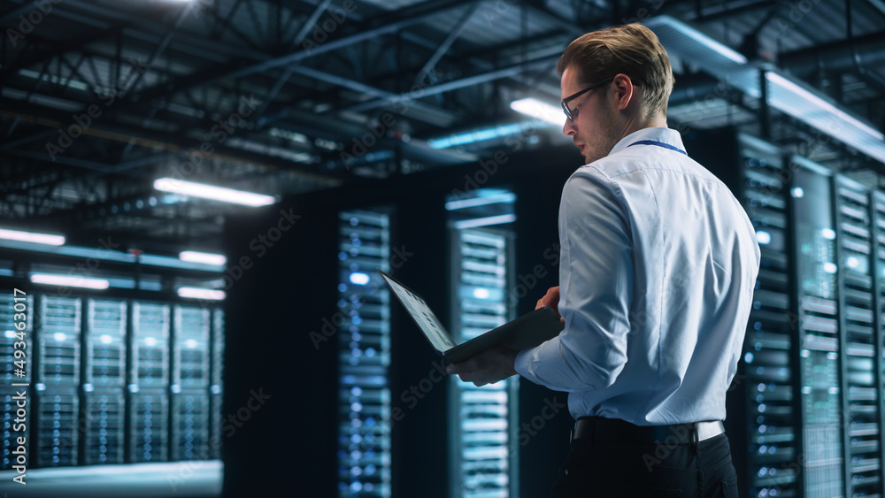 Poster creative caucasian man using a laptop computer in evening office. independent businessman is walking