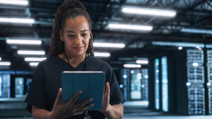 Portrait of the Cheerful Female IT Specialist Using Tablet Computer in Data Center, while Smiling...