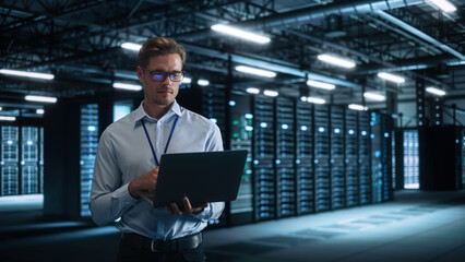 Male Engineer Programs Something and Holding Laptop Computer while Works in a Dark Modern High-Tech Office. High-Speed Data Transfer and Smooth Server Operation, Analytics, Statistics Concept