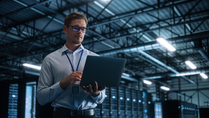 Successful Businessman Using Laptop Computer, Standing in Modern Dark Office Working on Financial,...