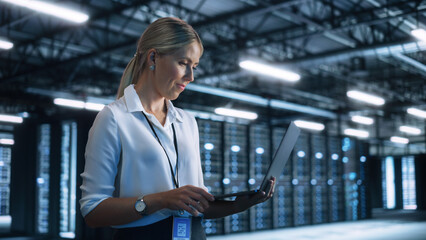 Concentrated Businesswoman or Manager Using Laptop Computer, While Standing in Dark Office or Hall and Working on Financial, Business and Marketing Projects. Business Concept