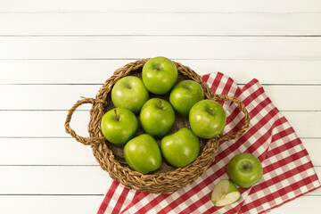 green apples in a wicker basket on a white background