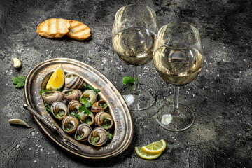 Escargots de Bourgogne or Snails with herbs, butter, garlic on metal plate with forks. wine glass....