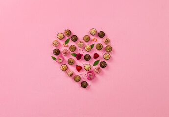 heart made of chocolates on pink background