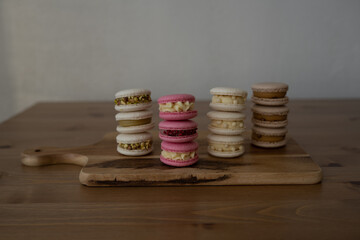 Colored sweet almond cookies, multicolored with cream, composition on a wooden table.