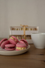 Pink sweet almond cookies with cream, a composition on a wooden table.