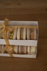 Sweet almond cookies with cream in a box, a composition on a wooden table.