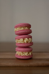 Pink sweet almond cookies, multicolored with cream, composition on a wooden table.
