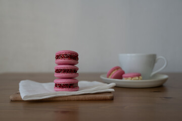 Pink sweet almond cookies, multicolored with cream, composition on a wooden table.