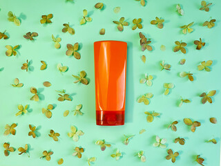 Unbranded orange shampoo and conditioner bottle for branding and label and dried hydrangea flowers on green background. Mockup, flatlay.