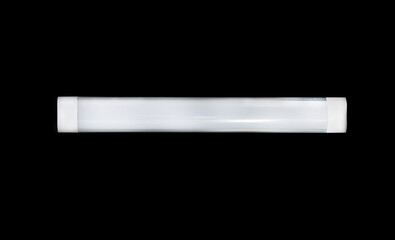 Long modern LED lamp with plastic housing isolated on black background