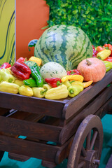 An abundance of vegetables and fruits. Natural food. Harvest in a garden wooden wheelbarrow, wooden cart with watermelons, pumpkins, peppers