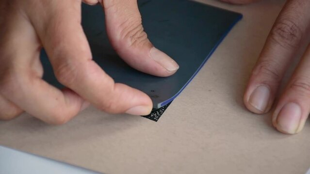 Woman lifting lino to reveal textured black print on brown texture paper