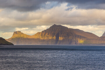 Sunset over the fjord and steep coast in Funnings, Faroe Islands, Denmark.
