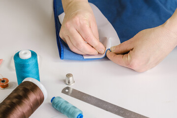 Seamstress makes a pattern out of fabric, basting the piece with pins