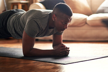 Make time for the things that benefit you. Shot of a young man practising yoga at home during the...