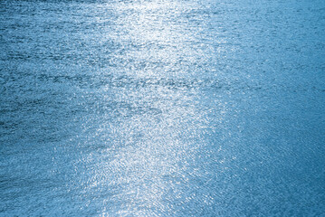 Sea ocean small wave with glitter reflection in sunset background blue color tone. Nature pattern background, peace, meditation concept.