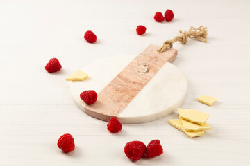 raspberry and round marble on white background