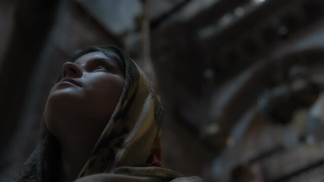 Young woman in traditional clothes standing inside the church and looking up. Slow motion.
