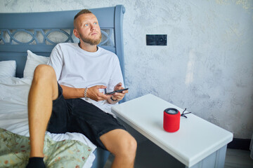 Male testing talking smart wireless speaker, man controlling home devices with a voice commands