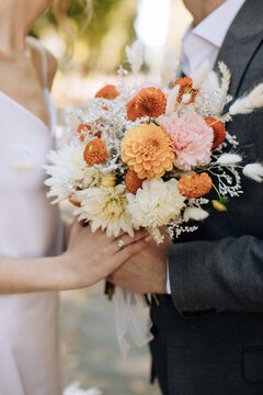 The bride and groom hold a beautiful wedding bouquet in a rustic style. Wedding accessories
