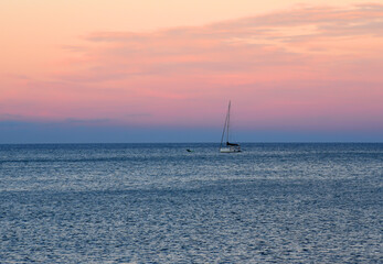 Fototapeta premium Sailboat at sea on sailing on the waves. Yachtsman during training on a sailboat. Skiff and Sailboat in sea port near the Spanish coast. Sail sport in Yacht club. Sail boat on waves on sunset in sea.