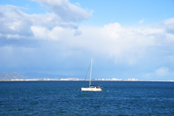 Fototapeta premium Sailboat at sea on sailing on the waves. Yachtsman during training on a sailboat. Skiff and Sailboat in sea port near the Spanish coast. Sail sport in Yacht club. Sail boat on waves on sunset in sea.
