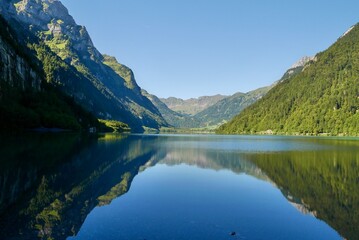 Naklejka na ściany i meble Reflection in idyllic mountain lake Kloentalersee in the Swiss Alps. Glarus, Switzerland.