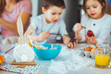 Family painting Easter eggs together at table. Laughing family on Easter. Happy young family with two children painting Easter eggs at home. Easter. Happy family