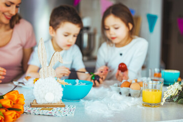Obraz na płótnie Canvas Happy young family decorating Easter eggs. Happy family spending time together during Easter holiday at home. Two cute kids painting easter eggs with mom and dad.