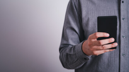 Close-up male hands using smartphone on gray empty space background. searching or social networks concept. online technology communication network.