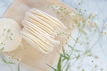 Reusable fabric sponges.Organic cotton reusable tissue cosmetic sponges and white gypsophila flowers on gray marble background.Eco-friendly bio natural cosmetics . reasonable consumption
