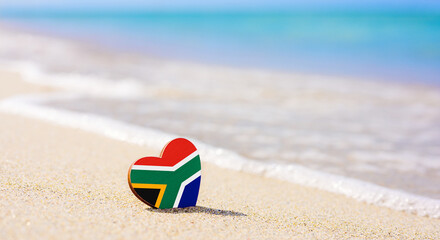 Flag of South Africa in the shape of a heart on a sandy beach. The concept of the best vacation in...