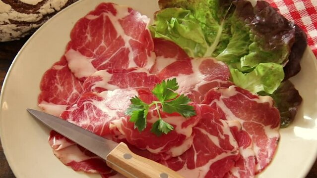 dish of coppa with a ball of bread on a wooden table