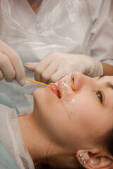 close up beauty procedure. permanent lip tattoo. master in white medical gloves check permanent lip tattoo on a model, side view. beauty concept, free space