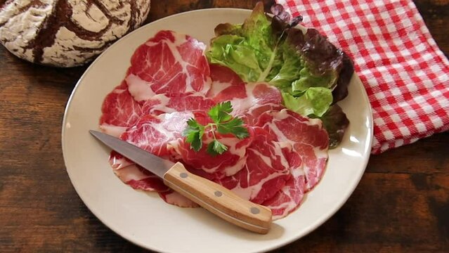 dish of coppa with a ball of bread on a wooden table