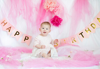 Obraz na płótnie Canvas Caucasian baby girl celebrating her first birthday in pink decorations. 