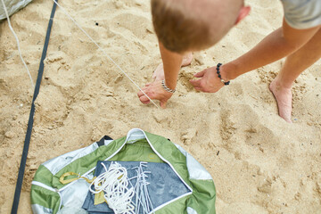 Young male tourist puts a green tent in the beach coast . The man sets up a camp on a hike