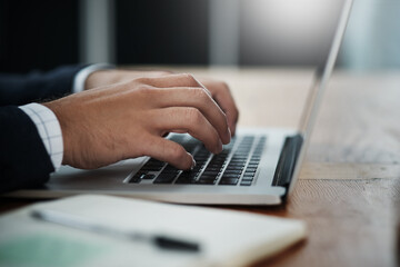 Technology helps him take charge of business. Closeup shot of an unrecognizable businessman working on a laptop in an office.