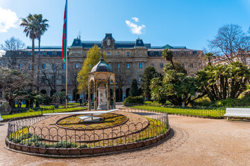 Obraz premium Gardens and clock of the Plaza Gipuzkoa in the center of San Sebastian, tourist city a spring morning. Gipuzkoa, Basque Country