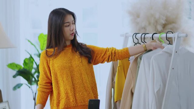 asian younf female small business online onwer social streaming lives selling cloth fashioned online in home studio,asia female entrepreneur selling shirt dress online talking to her client worldwide