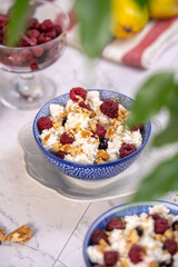 Blue bowl of cottage cheese with berries, honey and nuts for breakfast, selective focus.